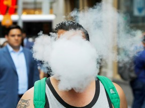 A man using a vape as he walks down the street in New York City.