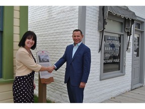 Laurene Mitchell of Heritage Park and Robin Lokhorst, Managing Partner of McLeod Law shake hands in front of the High River Law Office.