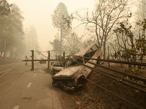 In this file photo taken on November 10, 2018 a fallen power line is seen on top of burnt out vehicles on the side of the road in Paradise, California after the Camp fire tore through the area.