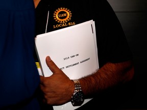 A member of the union carries a copy of the contract settlement agreement outside of the UAW GM Council Meeting held at the General Motors Renaissance Center in Detroit, Michigan, on October 17, 2019.