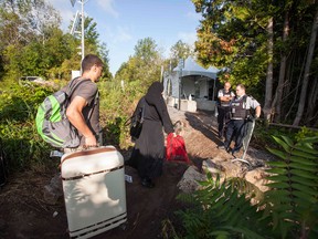 RCMP officers speak with people attempting to cross the US/Canada border illegally in near Hemmingford, Quebec, August 20, 2017.