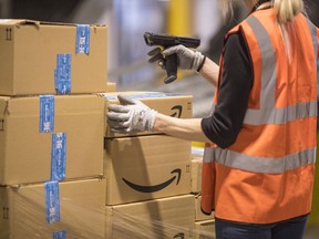 Amazon.com fulfilment centre employee checks packages. Warehouse real estate is on a roll as e-commerce grows.