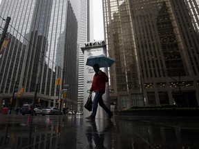 A pedestrian carries an umbrella while walking past signage for Home Trust Co., a subsidiary of Home Capital Group Inc., outside the company's headquarters in Toronto, on Thursday, May 4, 2017.
