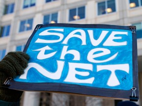 A woman holds a 'Save the Net' protest sign during a demonstration against the proposed repeal of net neutrality outside the Federal Communications Commission headquarters  in Washington, D.C. on December 13, 2017.