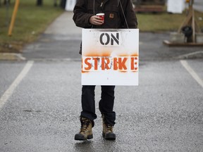 A Canadian National Railway Co. employee wears a "On Strike" sign in front of the Intermodal Terminals in Brampton, Ontario, on Nov. 19, 2019.