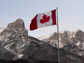 The Canadian flag flies over the Canadian Rockies at the Canmore Nordic Center in Canmore, Canada.
