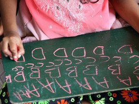 n Indian child writes with chalk on a slate during a lesson at a "bus-school" at a slum in the northern suburb of Malad in Mumbai.