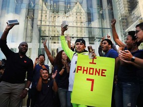 One of the first customers to buy a new iPhone 7 walks out of an Apple store in Manhattan on Sept. 16, 2016 in New York City. People around the globe waited in long lines to be among the first to purchase both the phone.