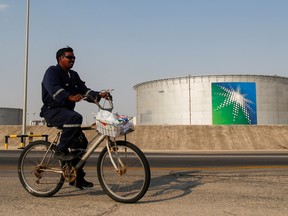 An employee rides a bicycle next to oil tanks at Saudi Aramco oil facility in Abqaiq, Saudi Arabia October 12, 2019. Saudi Aramco set the final price for its shares at the top end of the range, valuing the state-owned oil giant at US$1.7 trillion.