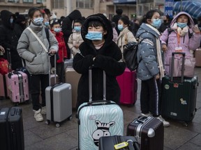Chinese children wear protective masks as they wait to board trains at Beijing Railway station before the annual Spring Festival on Jan. 21, 2020.