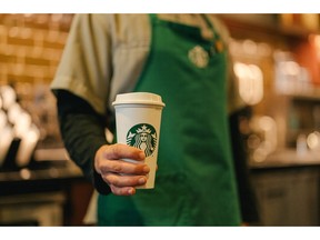 A Starbucks barista hands a reusable cup to a customer. As part of the company's new sustainability commitments, the company is working to encourage more use of reusable cups.