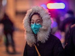 A woman wearing a protective mask walks on the street outside Beijing railway station in Beijing on January 22, 2020.