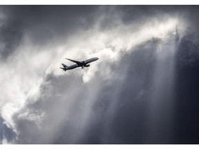 An Air Canada plane flies underneath dark clouds illuminated by some sun rays above Frankfurt, Germany, Thursday, March 2, 2017. Some experts say the Iran plane crash points to a glaring gap in rules around flight security, with states lacking incentives to close their own airspace and global agencies lacking the authority to preempt future tragedies.