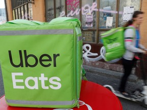 An Uber Eats food delivery courier rides a scooter.