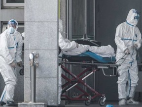 Medical staff members carry a patient into the Jinyintan hospital in China at the start of the Covid-19 outbreak.