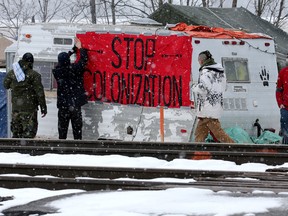 First Nations members of the Tyendinaga Mohawk Territory place a sign reading "Stop Colonization" to a camper at a blockade of train tracks servicing Via Rail, as part of a protest against British Columbia's Coastal GasLink pipeline, in Tyendinaga, Ont., February 13, 2020.