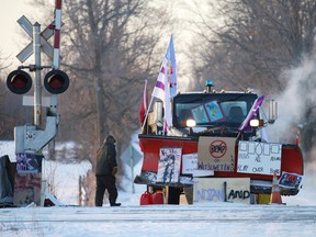 A man passes a snowplow in -23 Celsius (-9 Fahrenheit) temperatures at the camp of First Nations members of the Tyendinaga Mohawk Territory who continue to block Canadian National Railway (CN Rail) train tracks as part of a protest against British Columbia's Coastal GasLink pipeline.