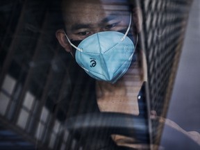A Chinese man wears a protective mask as he waits in a car in the Central Business District on February 3, 2020 in Beijing, China.