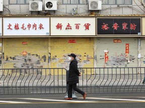 A man wearing a face mask walks past closed shops following an outbreak of the novel coronavirus in Wuhan, Hubei province, China.