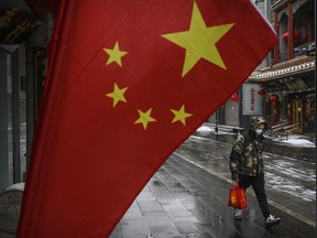 A Chinese man wears a protective mask as he walks during a snowfall in an empty and shuttered commercial street on February 5, 2020 in Beijing, China.