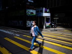 A pedestrian wearing a face mask crosses a street in Hong Kong.