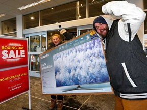 Francki Vanrooyen and Christopher Deklerk score a good deal on a big screen TV from Best Buy in Calgary. TVs have seen a price decline of 90 per cent in recent years.