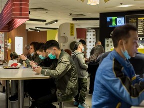 Customers wear protective masks inside a McDonald's Corp. restaurant in a shopping mall in Hong Kong in January. At McDonald's in Shanghai, customers have to sterilize their hands and register their contact information before they can pick up their food.