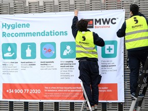 Workers install a banner with hygiene recommendations outside the Mobile World Congress MWC venue on February 12, 2020 at the Fira Barcelona Montjuic centre in Barcelona.