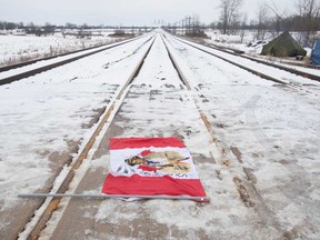 A Canadian maple leaf flag with native symbols on it lays on the train tracks in Tyendinaga Mohawk Territory, near Belleville, Ont., on Tuesday. Members of the Mohawk territory are blocking the CN/VIA tracks in support of Wet'suwet'en's blockade of natural gas pipeline in northern B.C.