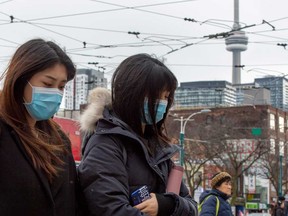 Pedestrians wear masks while walking in downtown Toronto as more positive Coronavirus patients have been confirmed.