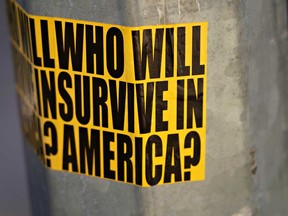 A sticker on a street lamp post in New York City on Sunday reading 'Who will survive in America?' as the coronavirus continues to spread across the United States.