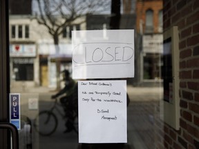 A closed sign is displayed on the door of a store on Queen St. in Toronto.
