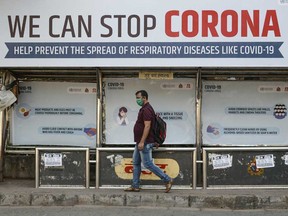 A man wearing a protective mask walks past a bus stop displaying preventive measures against the coronavirus in Mumbai, India.