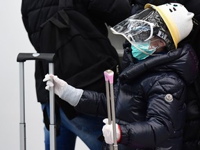 A passenger wearing a protective mask, protective glasses, a plastic face shield and gloves waits to check in at Milan's Linate airport on March 11, 2020, a day after Italy imposed unprecedented national restrictions on its 60 million people Tuesday to control the deadly COVID-19 coronavirus.