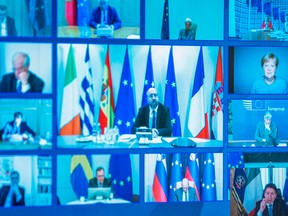 This photo of a television screen taken and handout by the press office of Palazzo Chigi on March 26, 2020 shows Italian Prime Minister, Giuseppe Conte, bottom right, European Council President Charles Michel, centre, German Chancellor Angela Merkel, right, and other world leaders taking part in a video conference as part of an extraordinary meeting of G20 leaders, from the Chigi Palace in Rome.