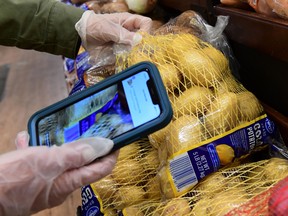 An Instacart worker uses her cellphone to scan barcodes showing proof of purchase for the customer while picking up groceries from a supermarket for delivery in North Hollywood, California.
