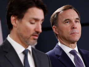 Finance Minister Bill Morneau, right, listens while Prime Minister Justin Trudeau speaks during a news conference on the coronavirus in Ottawa, on Wednesday.