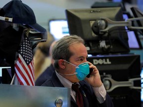 A trader wears a face mask on the floor of the New York Stock Exchange following traders testing positive for Coronavirus disease, in New York.