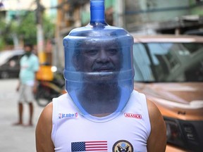 A resident using an improvised face shield made from a plastic water tank to protect him from the COVID-19 coronavirus pandemic walks in his neighbourhood in Manila on April 5, 2020, after the government imposed enhanced quarantine measures in the city.