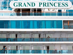 People look out from aboard the Grand Princess cruise ship, operated by Princess Cruises, as it maintains a holding pattern about 25 miles off the coast of San Francisco, California on March 8, 2020.