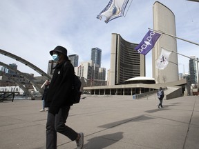 A small group of pedestrians pass through Nathan Phillips Square in front of Toronto City Hall as Torontonians adjust to the new normal. Many local businesses have closed their doors,  or they've asked their employees to work from home.