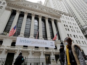 People walk by the New York Stock Exchange after more cases of coronavirus were confirmed in New York City, on March 12.