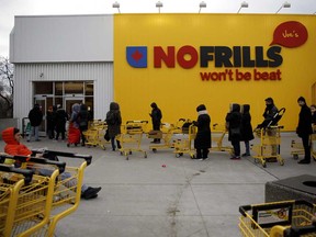Shoppers wait in line to enter a No Frills supermarket in Toronto on Saturday, March 14, 2020 as Canadians rush to stock up on supplies.