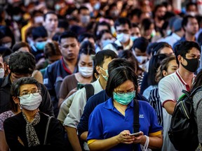 Commuters, wearing facemasks amid fears of the spread of the COVID-19 novel coronavirus, wait for a canal boat in Bangkok on March 2, 2020.