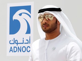An Emirati man is seen near the logo of ADNOC in Ruwais, United Arab Emirates.