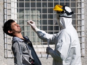 A member of the Slovak military takes a swab to test a man for COVID-19  outside a Roma settlement in the eastern Slovakian village of Janovce, on April 11, 2020.