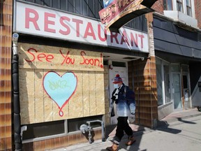 A man wearing a protective face mask passes a boarded up restaurant during the global outbreak of the coronavirus disease (COVID-19) in Toronto, Ontario.