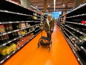 A shopper walks through an aisle empty of pasta, rice, beans and soup.