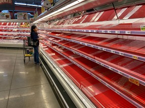 A shopper picks over the few items remaining in the meat section, as people stock up on supplies amid coronavirus fears, at an Austin, Texas, grocery store on March 13, 2020.