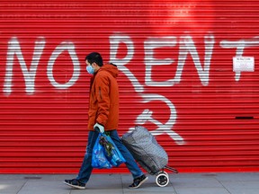 A pedestrian, wearing a protective face mask, passes graffiti on a shuttered business reading "no rent" in London, U.K., on Friday, March 27, 2020.